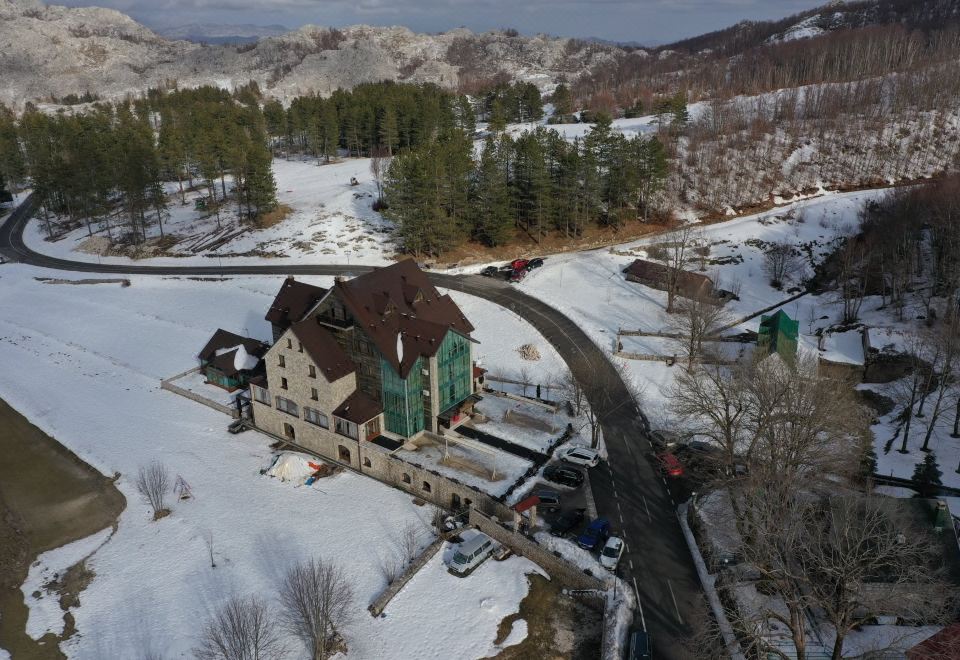 a large house is surrounded by snow - covered mountains and trees , with a winding road leading to it at Hotel Monte Rosa