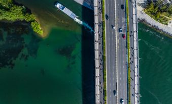 At sunset, an aerial view captures cars on a bridge with water in the foreground at WING HOTEL