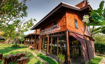 "a wooden building with a sign that says "" sangkhlaburi restaurant "" on the front , surrounded by trees and grass" at Maikaew Damnoen Resort
