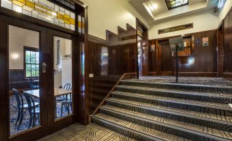 a grand staircase with wooden paneling , leading up to the second floor of a building at Nightcap at Pymble Hotel
