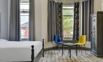 a bedroom with a large bed , two chairs , and a window , all decorated in white and blue at Empire Hotel