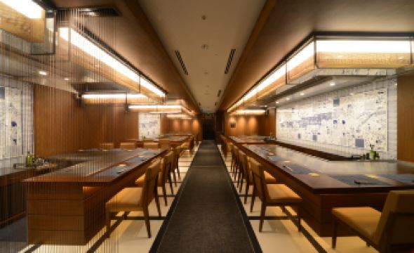 a modern , minimalist restaurant with wooden furniture and a long dining table , illuminated by overhead lights at Kobe Portopia Hotel