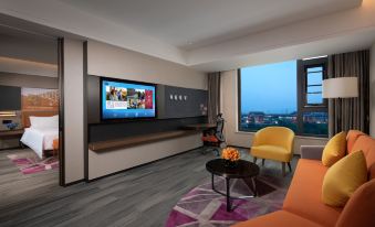 The living room, featuring large windows, a TV, and a chair in the center, is oriented towards an entertainment area at Hampton by Hilton Beijing Guomao CBD