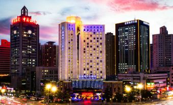 a tall hotel building surrounded by tall buildings and a body of water , creating a picturesque scene at Lanzhou Feitian Hotel (Lanzhou University Subway Station)