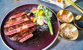 There is another plate with steak, salad, and other food placed beside it at Dayin International Youth Hostel（East Nanjing Road & The Bund）