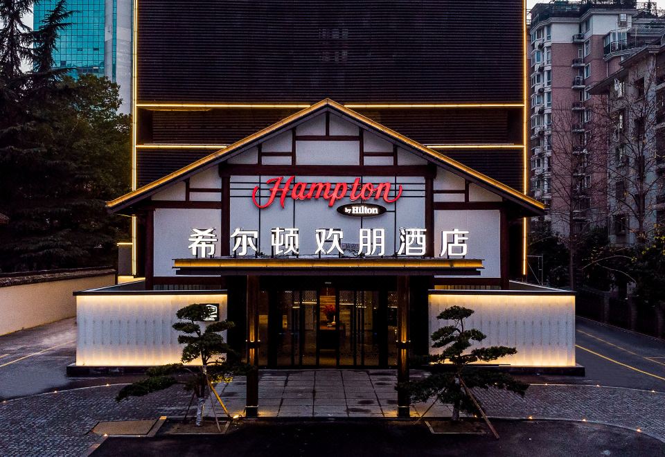 "The restaurant's front entrance is illuminated at night, displaying a sign that reads ""hotel"" above it" at Hampton by Hilton