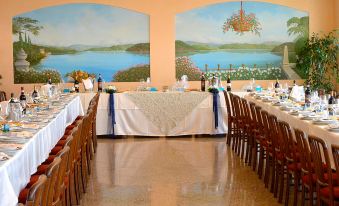 a dining room set up for a wedding reception , with tables covered in white tablecloths and chairs arranged around them at Hotel Marina