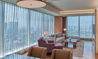 a modern living room with large windows , wooden floors , and comfortable seating arrangements under a hanging light at Grand Hyatt Manila