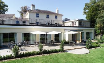 a white building with a balcony and an outdoor dining area with tables , chairs , and umbrellas at Alton House Hotel