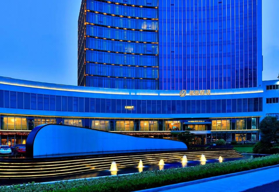 A large building with an illuminated exterior view at night at Yindu Hotel