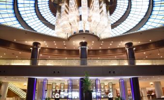 a luxurious hotel lobby with high ceilings , large windows , and multiple chandeliers , as well as a staircase leading to the upper floors at Kobe Portopia Hotel