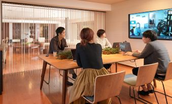 a group of people sitting around a table in a room , working on their computers at Lake Akan Tsuruga Wings