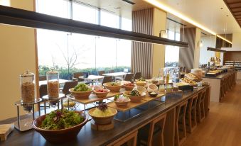 a long dining table filled with a variety of food , including bowls , plates , and cups at Hotel Clad