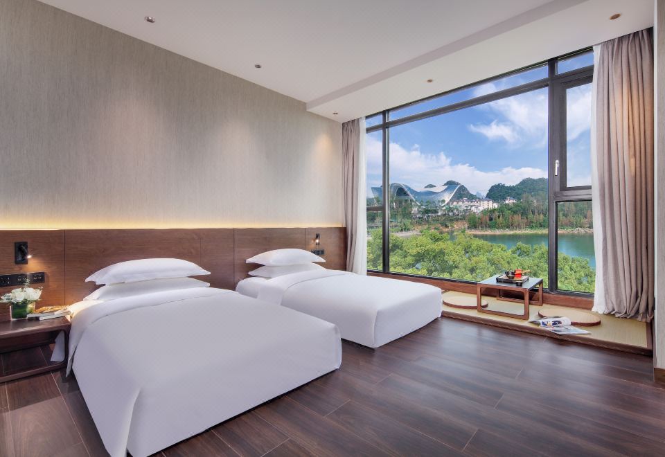 a modern bedroom with double beds and large windows overlooking the city at WING HOTEL