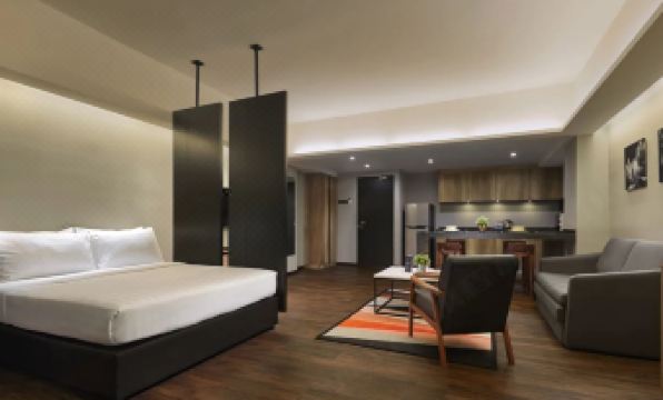 a modern bedroom with a white bed and black walls , a gray chair , and a dining area at Tropics Eight Suites
