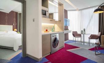 a modern kitchen with a washing machine and a dining table in the background at Burgu Arjaan by Rotana