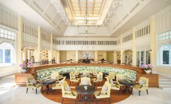 a large , well - lit hotel lobby with multiple couches and chairs arranged around a circular reception desk at Dheva Mantra Resort