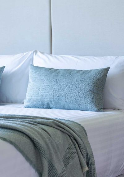 a white bed with a blue pillow and blanket , creating a cozy and inviting atmosphere at Oval Hotel at Adelaide Oval, an EVT hotel