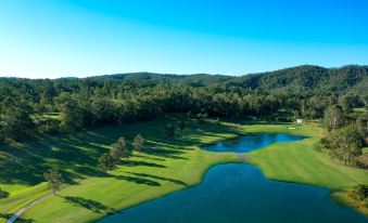aerial view of a golf course with a lake in the background , surrounded by trees at The Kooralbyn Valley