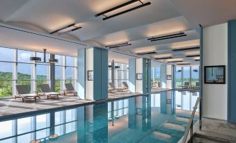 A large swimming pool is located in the middle of the room, with floor-to-ceiling windows providing a view of an indoor area at Andaz Shenzhen Bay