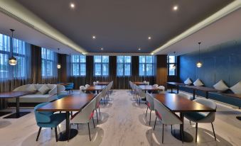 A restaurant with large windows and tables in the middle, alongside an area rug that at Orange Hotel (Shanghai Pudong Airport)