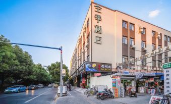 There are buildings, stores, and parked cars on a street at an intersection at Ji Hotel (Shanghai Hongqiao Shuicheng Road)