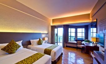 a hotel room with two beds , a desk , and a window overlooking a beautiful view at Thistle Port Dickson Resort