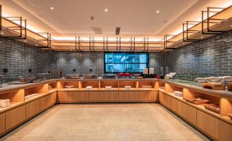 A restaurant with large windows and tables in the middle, alongside an open kitchen at Qiuguo Hotel (Beijing Sanlitun Gongti Branch)