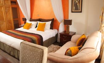 a bedroom with a bed , two chairs , and a couch , all decorated in a warm and inviting color scheme at Marble Arch Hotels