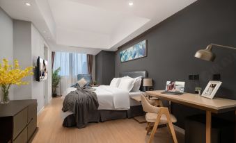 A modern bedroom with a large bed and desk in the middle, alongside an open space at Citadines Apart Hotel (Shanghai Yan'an West Road)