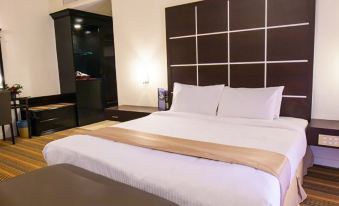 a large bed with white linens and a brown headboard is in a room with wooden floors at Amverton Heritage Resort