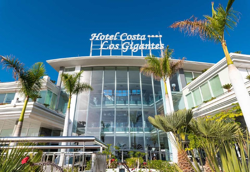 the hotel costa dos gigantes in cancun , mexico , a modern and unique building with a glass exterior and palm trees surrounding it at Landmar Costa Los Gigantes