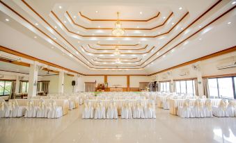 a large , empty banquet hall with white tablecloths and chairs set up for an event at Chiangkhan River Mountain Resort