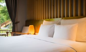 a well - lit hotel room with a large bed and white linens , along with two lamps on either side of the bed at Alba Wellness Resort by Fusion