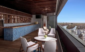 a balcony overlooking a body of water , with a dining table and chairs set up for a meal at Melia Vinpearl Hue