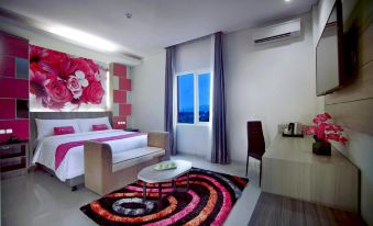 a modern hotel room with a bed , couch , table , and window , decorated with colorful rugs and artwork at favehotel Langko Mataram - Lombok