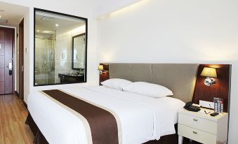 a large bed with a brown blanket and white sheets is in a room with wooden floors at Java Palace Hotel