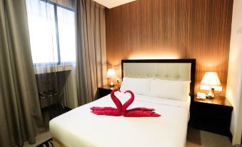There is a bedroom with a double bed and red towels on the side, accompanied by an orange at The Grand Campbell Hotel Kuala Lumpur