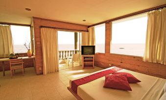 a spacious bedroom with a large bed , a tv , and a view of the ocean at Antulang Beach Resort