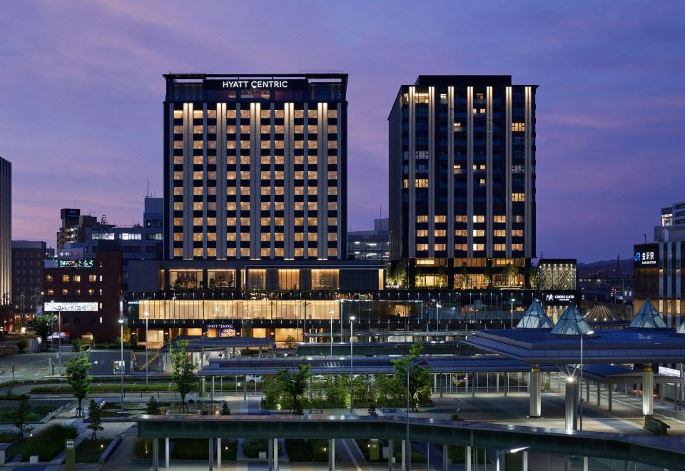 A night time lapse photo of a large building with two tall buildings in the background at Hyatt Centric Kanazawa