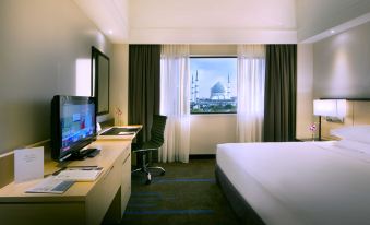a hotel room with a king - sized bed , a desk , a tv , and a window overlooking the city at Concorde Hotel Shah Alam