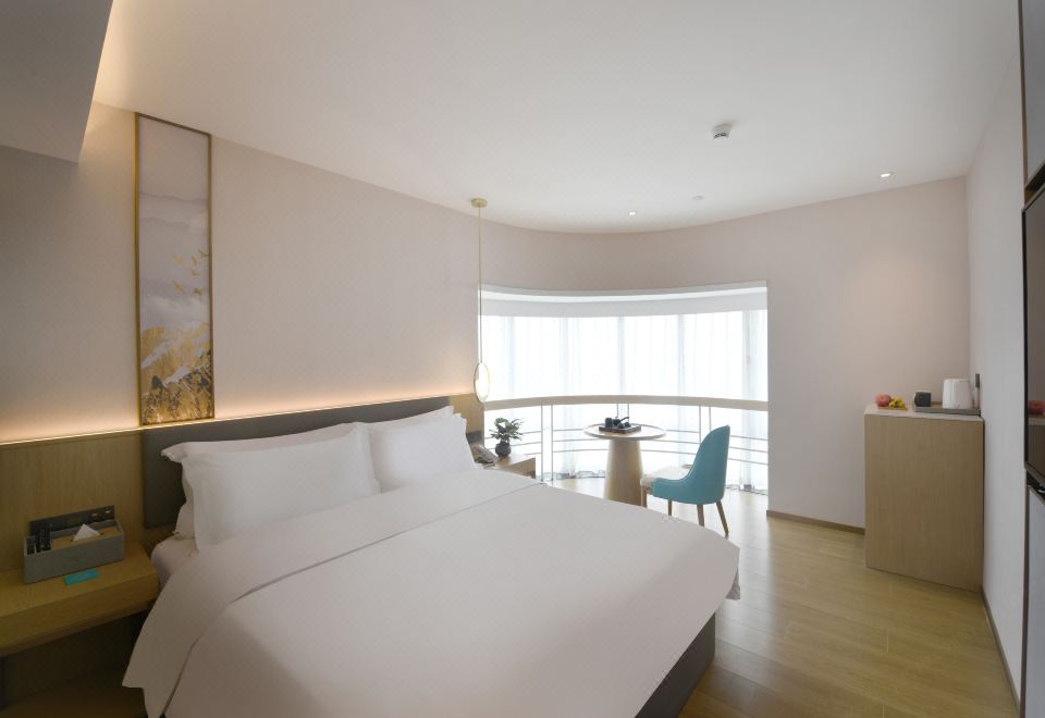 A modern bedroom with large windows features a white bed and a matching chair in the center at Hangtai Hotel (Shenzhen Science Park Window of the World)