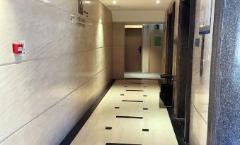 In an apartment or modern building, there is a long hallway with doors and tiled floors at Hangtai Hotel (Shenzhen Science Park Window of the World)