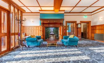 a cozy living room with two couches , a coffee table , and a fireplace , decorated with wood paneling and green accents at Woodland Manor Hotel