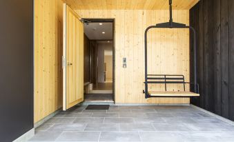 a wooden cabin with a stone floor , a black swing hanging from the ceiling , and a door leading to another room at Birchwood Chalet