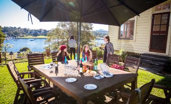 a group of women are sitting around a dining table on a patio , enjoying a meal together at Cockatoo Island Accommodation