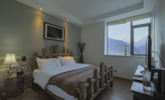 The bedroom features large windows, a wooden bedspread, and double-sized white sheets at Hotel Blanche Yading