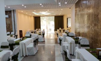 a large dining room with white tables and chairs set up for a formal event , possibly a wedding reception at Richmind Hotel