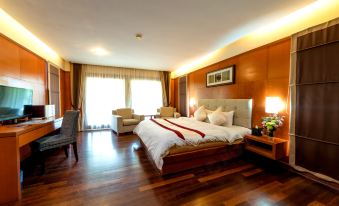 a large bed with white linens is in a room with wooden floors and walls at Duyong Marina & Resort
