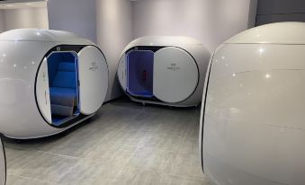 The room has a futuristic design with white walls and blue accent lighting at Ke Sleeping Lounge (Beijing Daxing Airport Terminal)